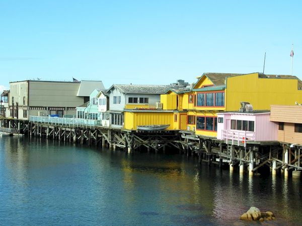 Colorful houses on stilts along a calm harbor, pastel blues, yellows, and pinks lining the water’s edge.