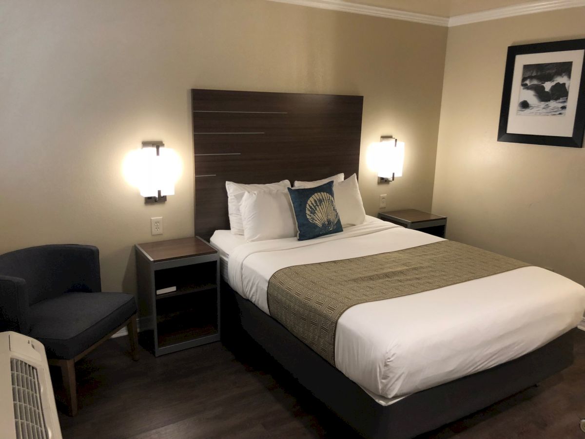A hotel room with a neatly made bed, two bedside lamps, a chair, nightstands, and framed wall art. Top it at 140 characters, always ending the sentence.